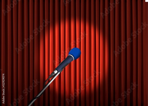 Microphone under spotlight over red curtains
