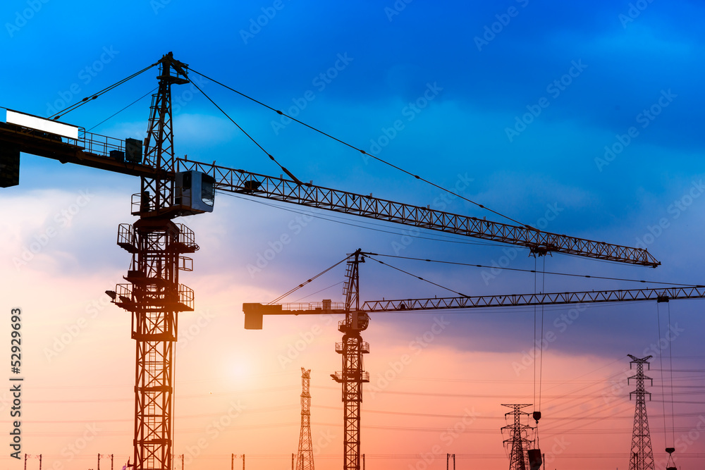 Industrial construction cranes and building silhouettes 