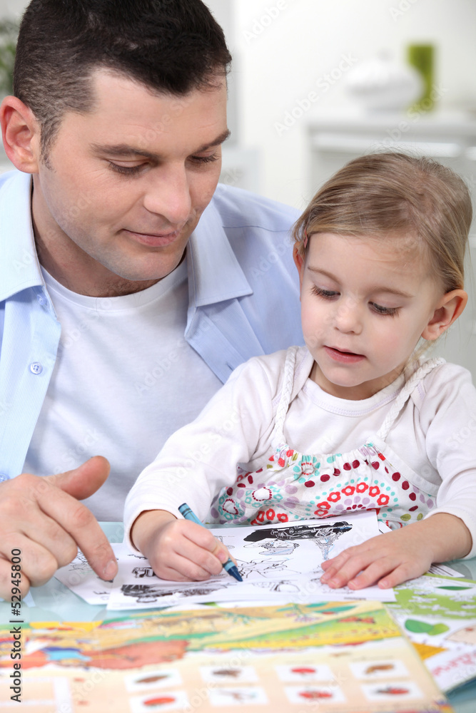 little girl colouring under dad's watchful eye little girl colouring under dad's watchful eye
