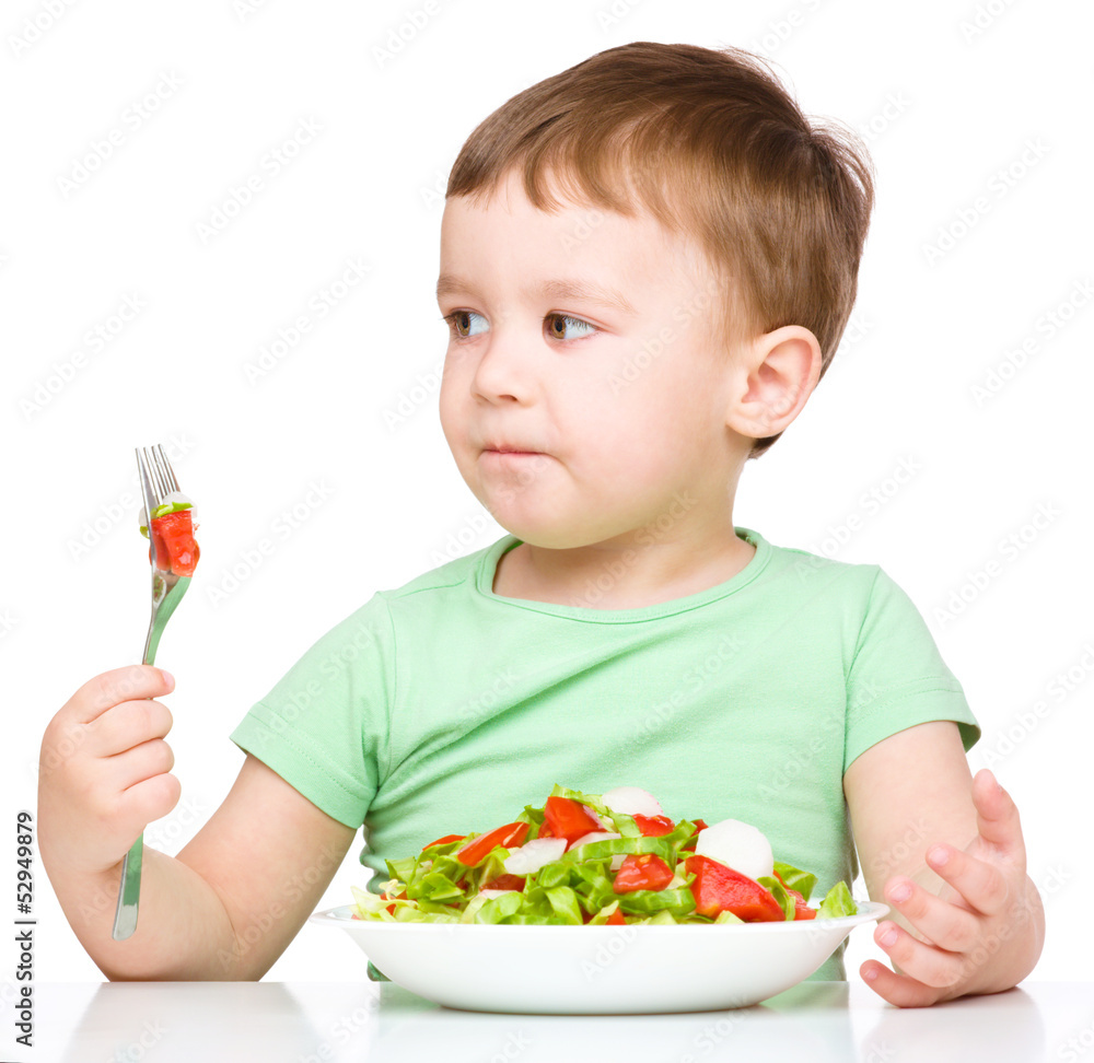 Cute little boy is eating vegetable salad Cute little boy is eating vegetable salad