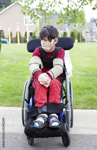 Disabled little boy in wheelchair outdoors