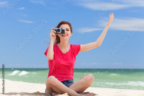 Redhead teen girl with retro camera on the beach