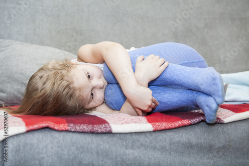 Small Caucasian defenseless child huddled on the couch photo