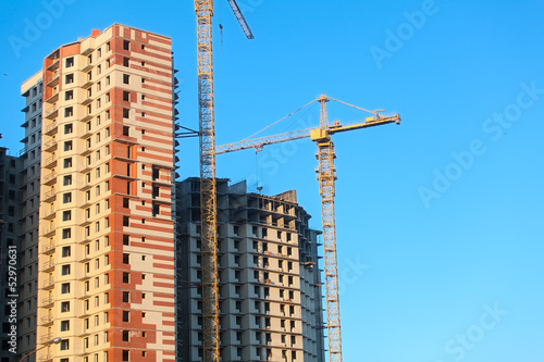 Construction of highrise buildings with cranes. Blue sky