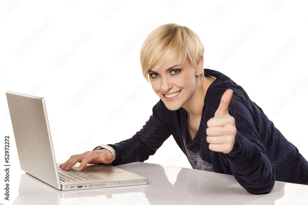 smiling blonde working on a laptop and showing thumbs up smiling blonde working on a laptop and showing thumbs up