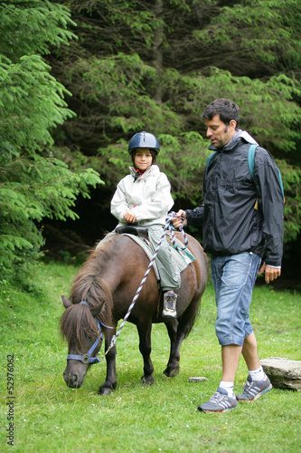 Father helping his daughter ride a pony