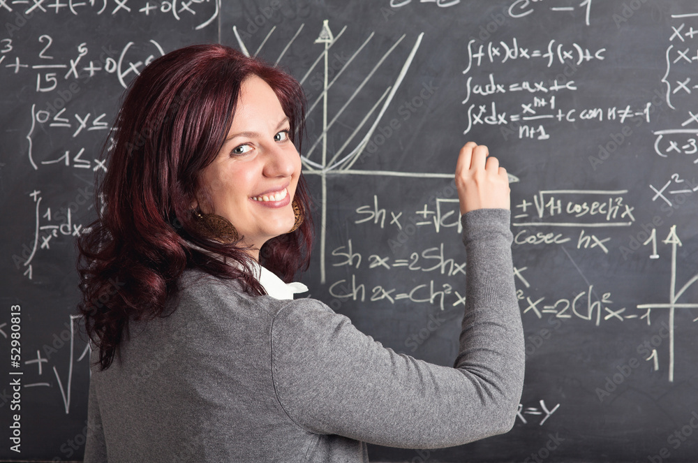 smiling caucasian female teacher with red hair. sociable look. blackboard on the background. teaching and school concept. smiling caucasian female teacher with red hair. sociable look. blackboard on the background. teaching and school concept.