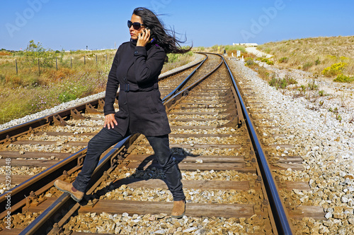 Beautiful woman phoning at a railroad track photo