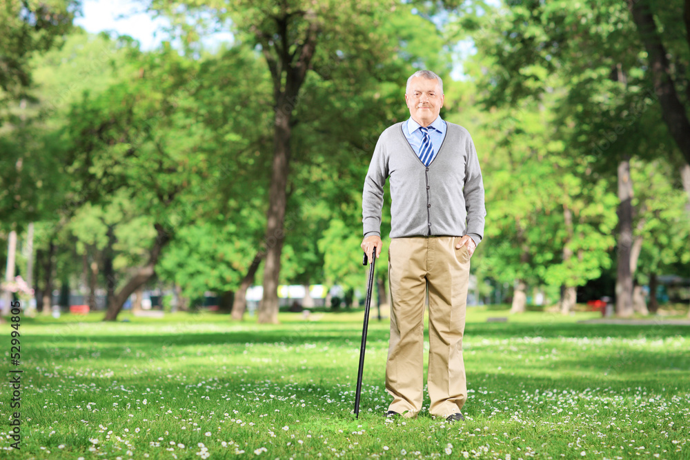 Full length portrait of a senior man walking with a cane in park