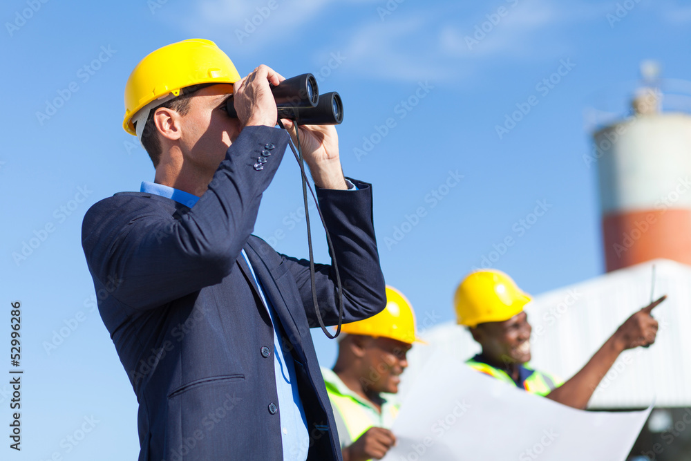 architect using binoculars looking at construction site architect using binoculars looking at construction site