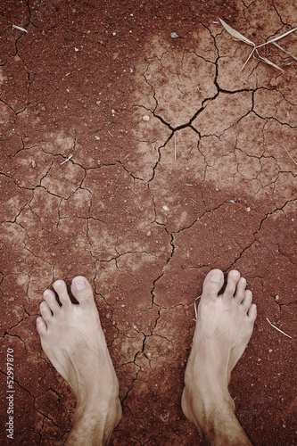 Barefoot standing on dry and cracked earth background