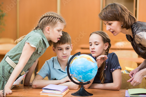 pupils studying a globe together with teacher