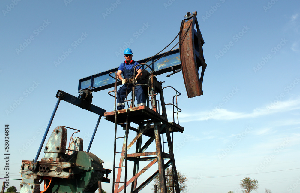 strong oil worker standing on pump jack strong oil worker standing on pump jack