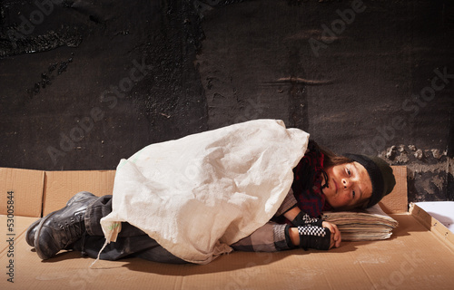 Fotografie Beggar boy sleeping on cardboard sheet