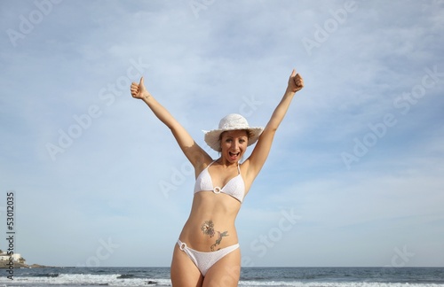 young woman at the beach with thumbs up