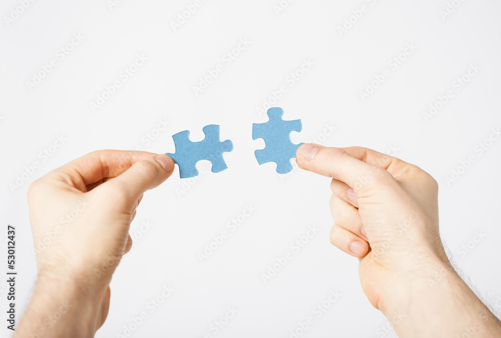 two hands trying to connect puzzle pieces two hands trying to connect puzzle pieces