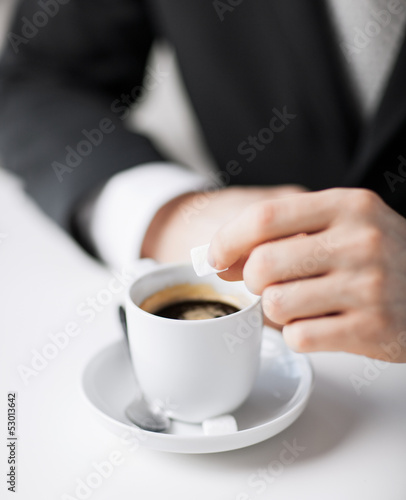 man putting sugar into coffee