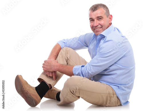 casual middle aged man sits and smiles at you