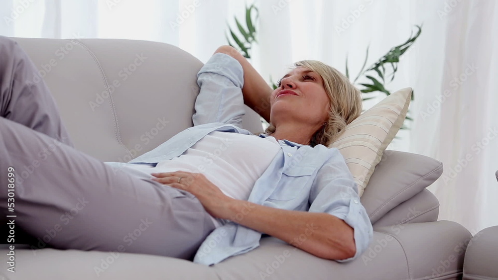 Woman smiling and relaxing on sofa Woman smiling and relaxing on sofa