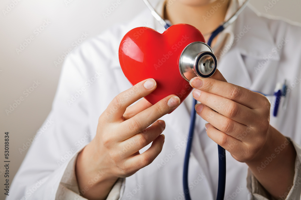 A doctor with stethoscope examining red heart - obrazy, fototapety, plakaty 