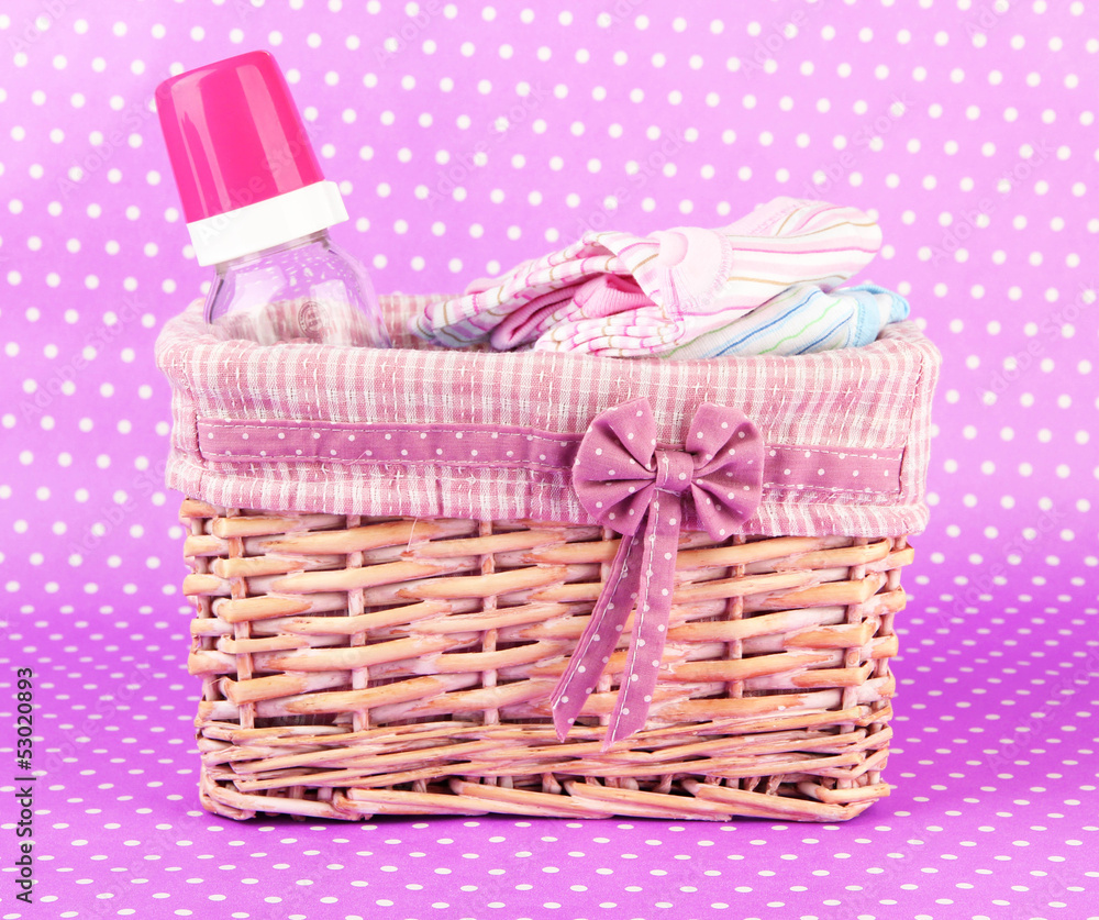 Beautiful basket of baby clothes on a pink background Beautiful basket of baby clothes on a pink background