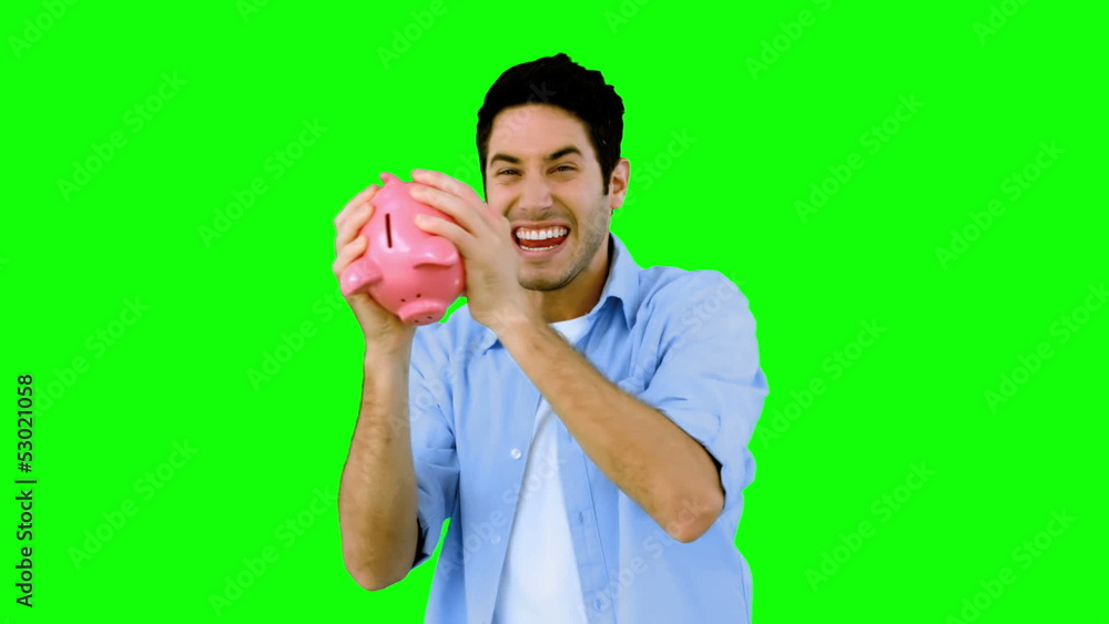 Man shaking piggy bank excitedly on green screen Man shaking piggy bank excitedly on green screen