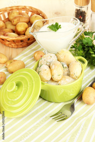 Tender young potatoes with sour cream and herbs in pan