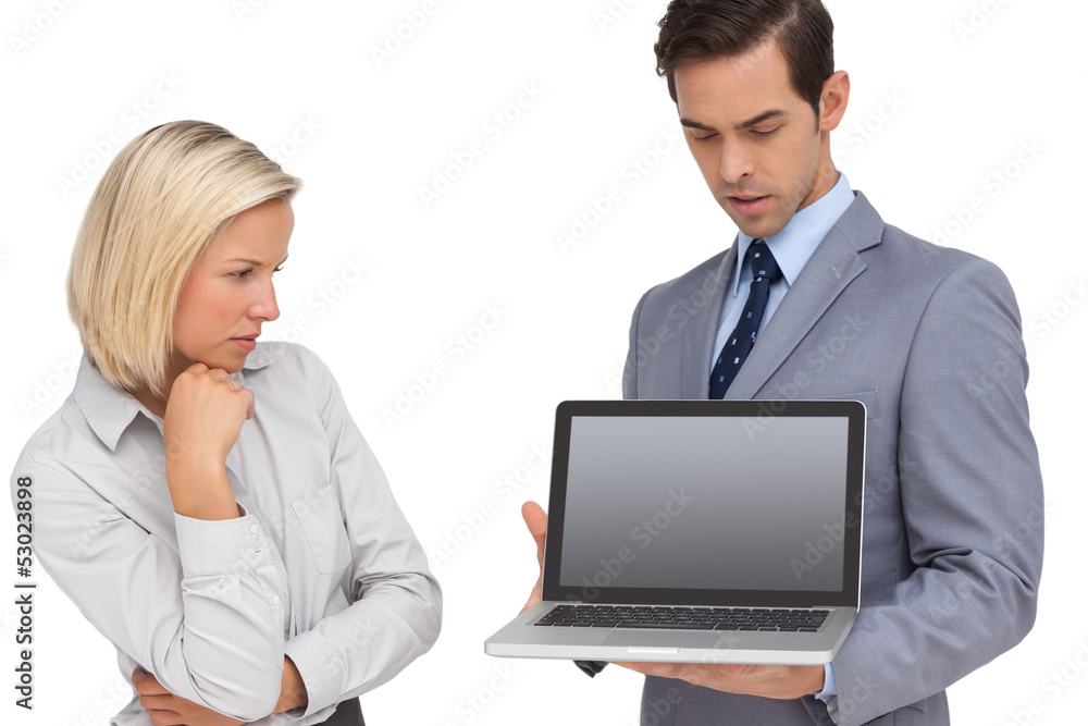 Businesswoman looking at laptop held by her colleague Businesswoman looking at laptop held by her colleague