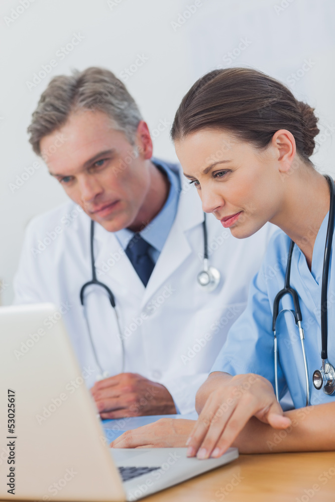 Two doctors focused on a laptop screen Two doctors focused on a laptop screen