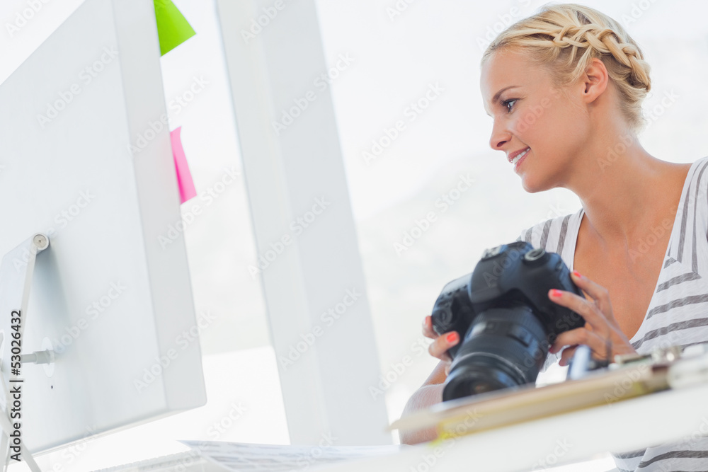 Attractive photo editor looking at a digital camera