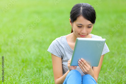 Woman setting on grass with tablet