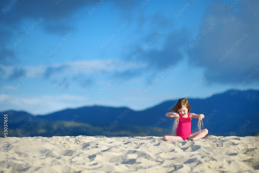 Adorable little girl playing on a sandy beach