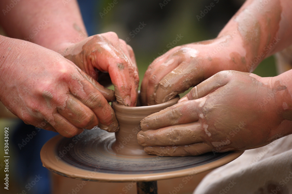 hands of a potter, creating an earthen jar on the potter's wheel