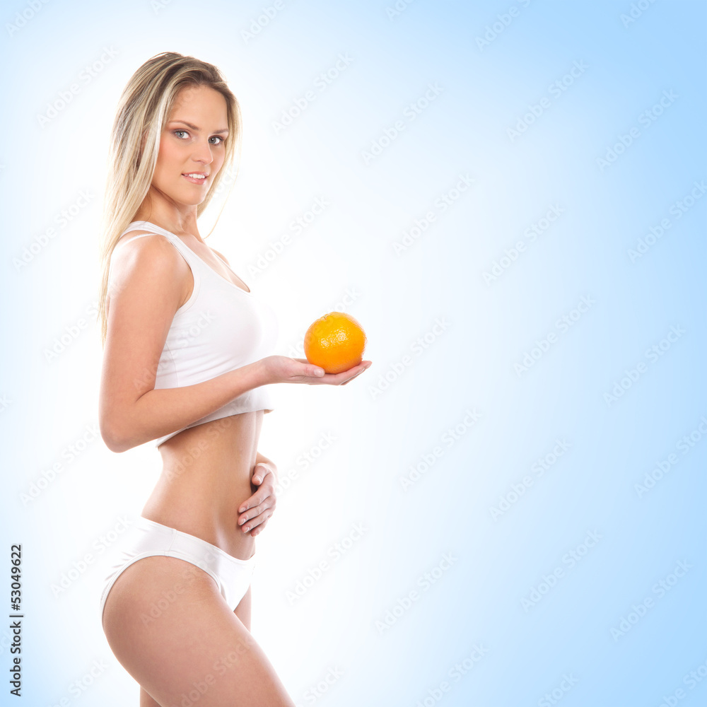 A young sexy woman in sporty clothes holding an orange A young sexy woman in sporty clothes holding an orange