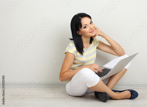 Beautiful young woman sitting with notebook in room