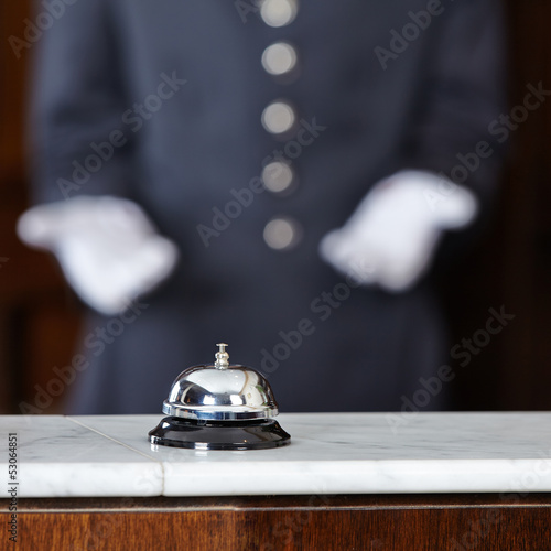 Concierge zeigt auf Tischglocke