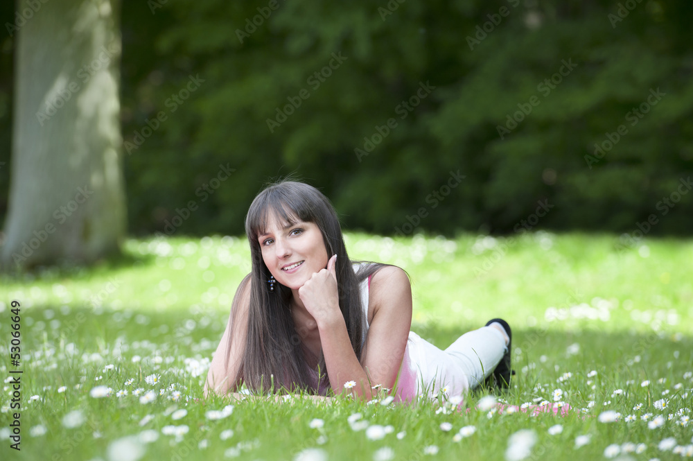 young woman lying down in a grassfield wth daisies young woman lying down in a grassfield wth daisies