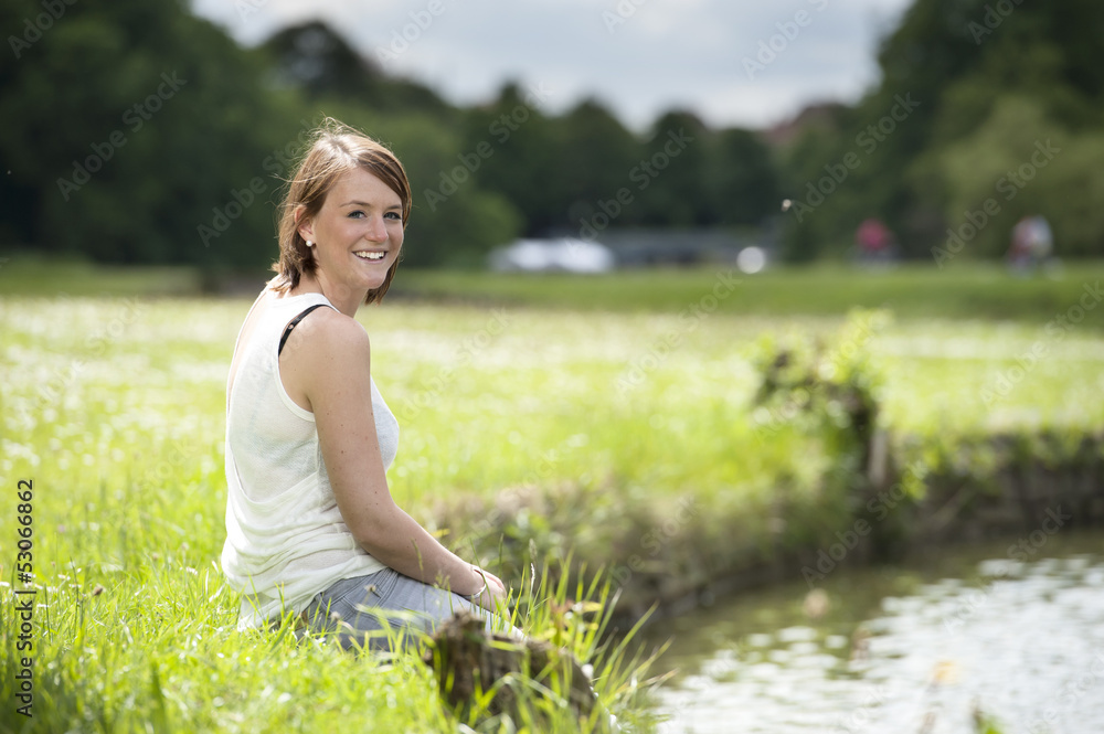 young woman in white seated at the lake