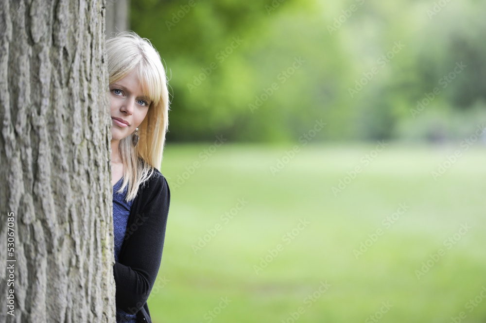 beautiful young woman hiding behind a tree beautiful young woman hiding behind a tree