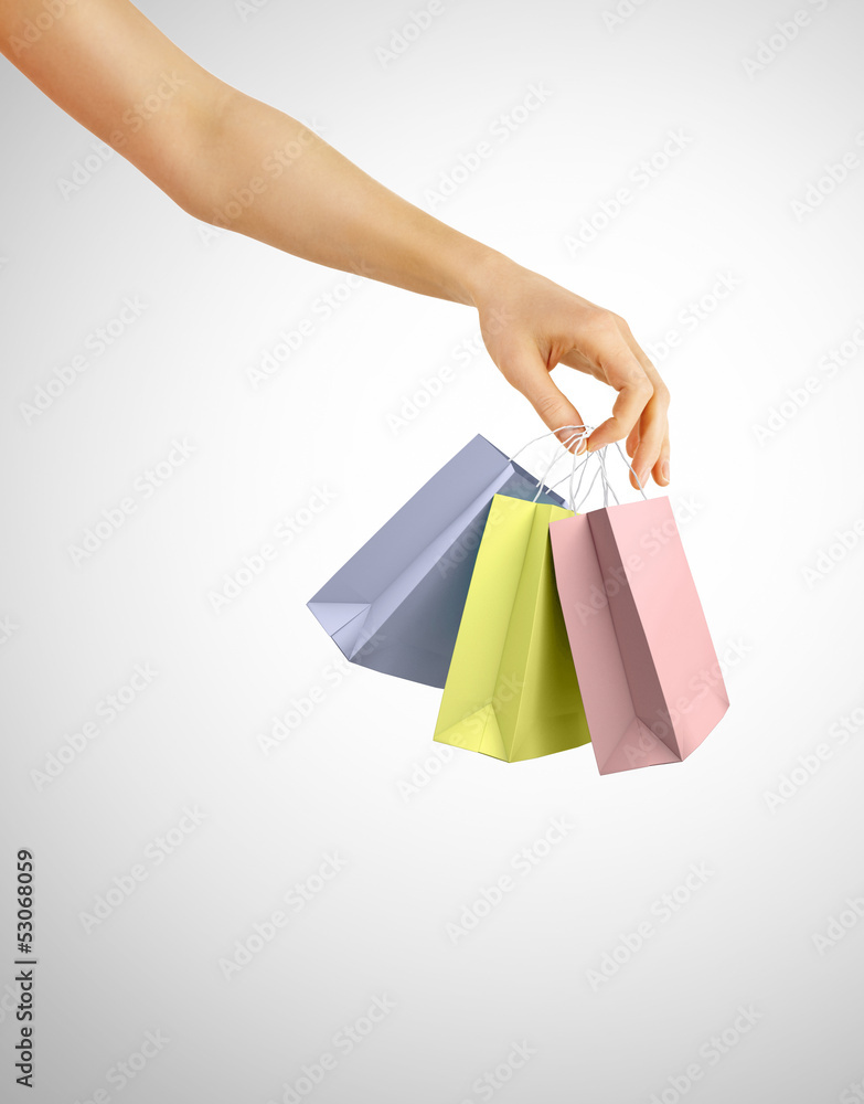 Hand with color shopping bags on gray background