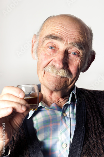 Cheerful old man with blue eyes making a toast