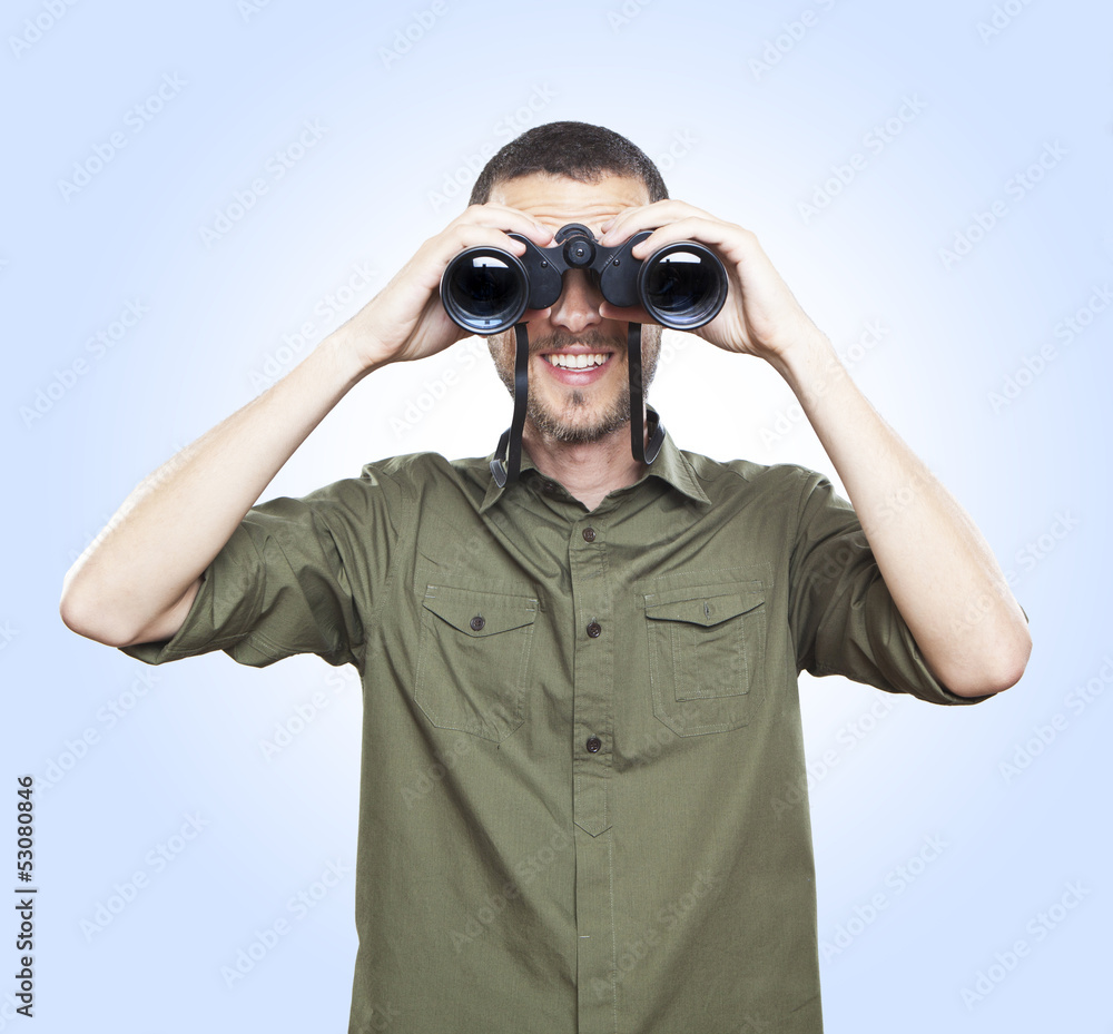 young man looking with binoculars, cheerful face expression young man looking with binoculars, cheerful face expression