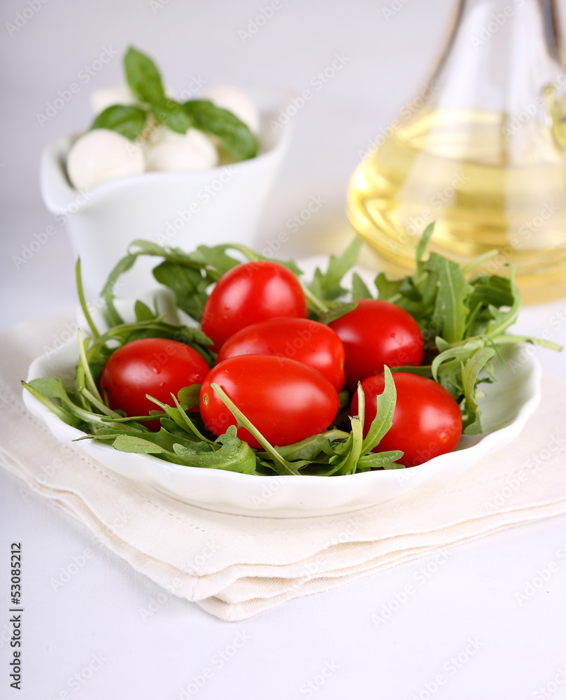 Ingredients for salad with arugula, tomatoes and mozzarella mini Ingredients for salad with arugula, tomatoes and mozzarella mini