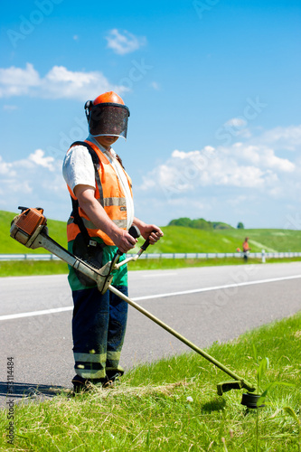 Road landscapers cutting grass using string lawn trimmers photo