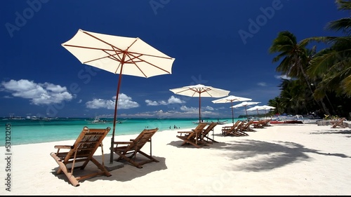 Sun umbrellas and beach chairs on coasline  photo