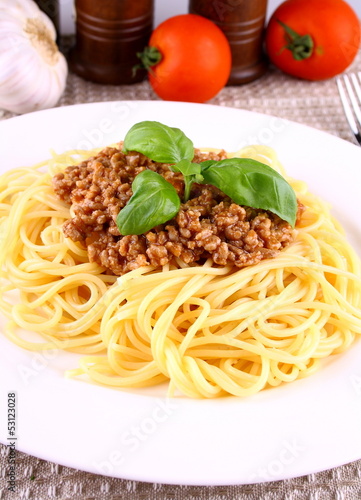 Delicious spaghetti bolognese with basil leaves on white plate