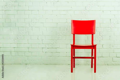Red chair in empty room against a brick wall with copy-space