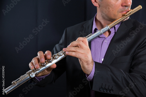 professional flutist musician playing flute on black background