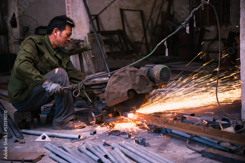 Chinese worker cutting metal