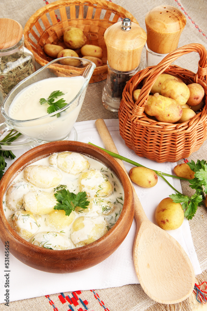Tender young potatoes with sour cream and herbs in wooden bowl Tender young potatoes with sour cream and herbs in wooden bowl